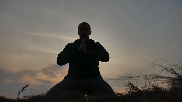 religion concept. silhouette of a male monk engaged in meditation at sunset sunlight. Buddhist prayer at sunset healthy lifestyle way of life nature
