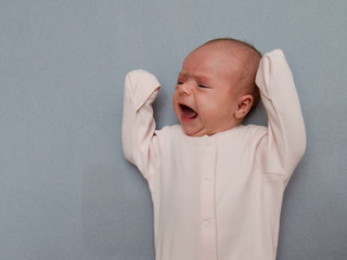 Portrait of a newborn baby who cries with copyspace. Close-up.