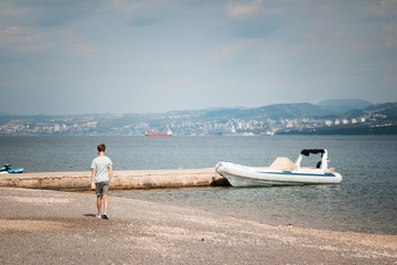 child by the sea. child on the beach. is walking along the shore. Goes along the path (parapet)....