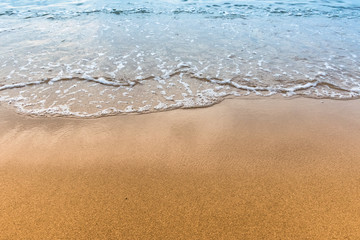 Soft wave of blue ocean on sandy beach.