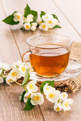 Glass cup of green tea with white jasmine flowers.