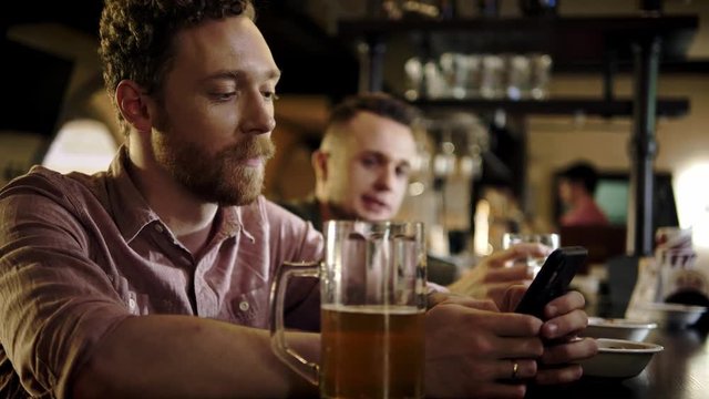 Man with a mobile phone drinking draft beer in a pub