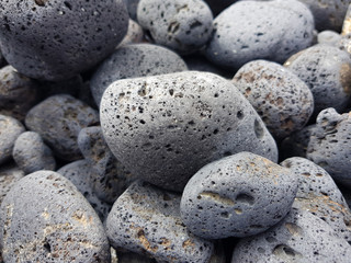 Fototapeta na wymiar Volcanic rocks rounded by the aleaje of the sea on a beach in Lanzarote, Spain