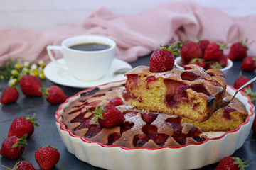 Open strawberry pie placed in ceramic shape on a dark background