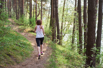 Obraz premium Athletic young woman in pink sneakers run in spring forest