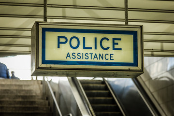 Police assistance sign hanging from ceiling in underground train station