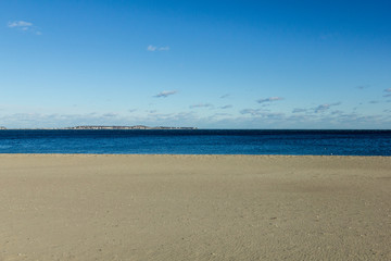 Fototapeta na wymiar Empty beach with calm deep blue water and clear sky