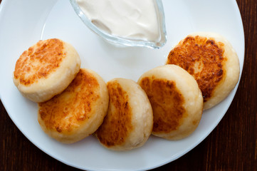 Fried cheese pancakes with sour cream view from above, close-up. For cafe or restaurant menu design.