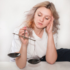 a girl with scales in her hands on a light background makes a decision, weighs the arguments