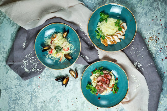 Blue plates with risotti. Gray light textured background. Beautiful serving dishes. Restaurant menu