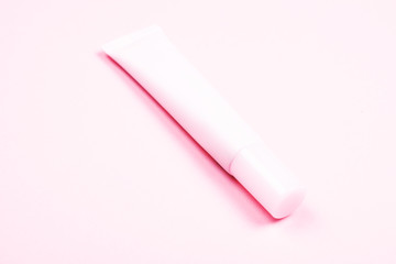 Pastel pink cosmetic tube on the background of the same tone. Body care and beauty concept.
