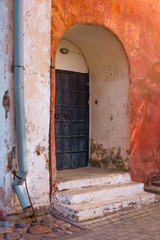 Fototapeta na wymiar Vintage red wall with arch gate. Old door, building exterior.