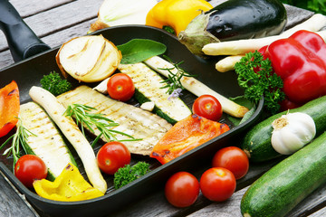 grilled vegetables in grill pan with raw vegetables