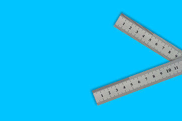 Pair of metal straightedges with digits and scale on blue background with copy space for your text