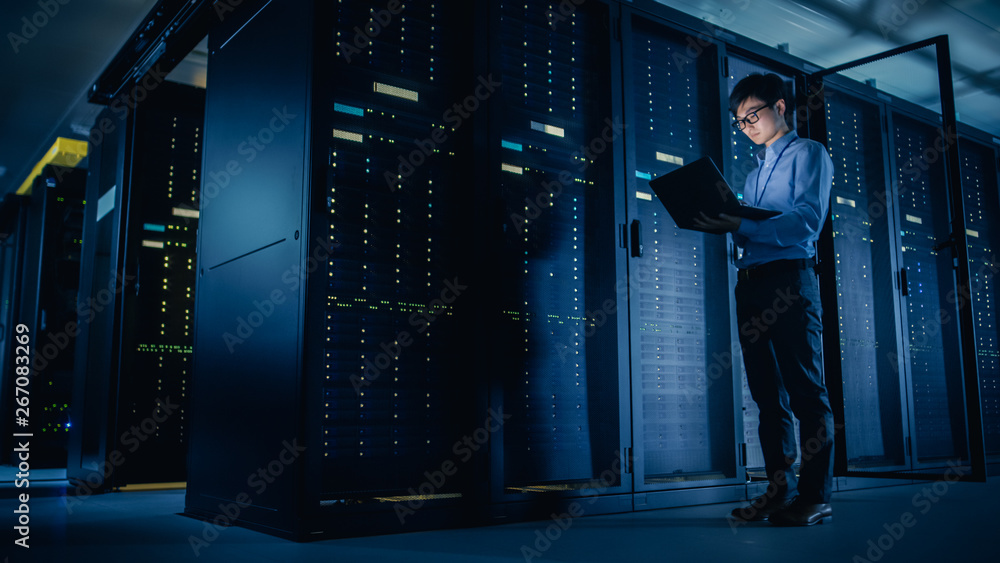 Aufkleber In Data Center: Male IT Technician Running Maintenance Programme on a Laptop, Controls Operational Server Rack Optimal Functioning. Modern High-Tech Telecommunications Operational Super Computer.