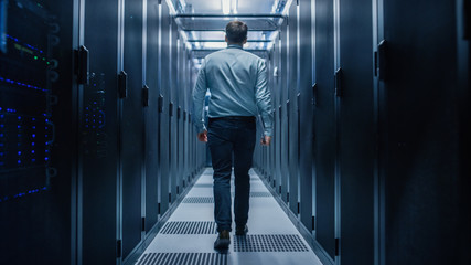 IT Engineer Walking Through Data Center with Working Server Rack to Do Routine Maintenance Check with Laptop. Concept of Cloud Computing, Artificial Intelligence, Supercomputer - Powered by Adobe