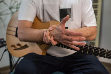 Fototapeta na wymiar Musician having wrist pain while playing electric guitar in home music studio.