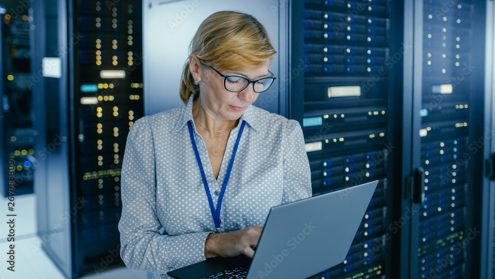 Poster Portrait Shot In Data Center: IT Technician Running Maintenance Programme on a Laptop, Controls Operational Server Rack Optimal Functioning. Modern High-Tech Telecommunications Operational Data Center