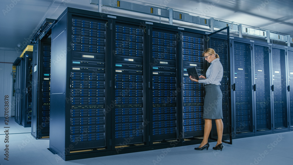Poster In Data Center: Female IT Technician Stand Near Opened Rack Cabinet and Runs Maintenance Program on Laptop, Controls Operational Server's Optimal Functioning. 