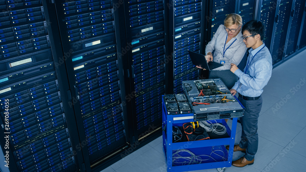 Poster In the Modern Data Center: Engineer and IT Specialist Work with Server Racks, on a Pushcart Equipment for Installing New Hardware. Specialists Doing Maintenance and Diagnostics of the Database.