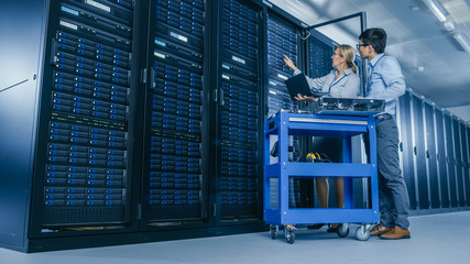 In the Modern Data Center: Engineer and IT Specialist Work with Server Racks, on a Pushcart...