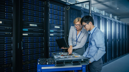 In the Modern Data Center: Engineer and IT Specialist Work with Server Racks, on a Pushcart...