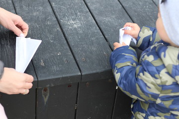 hands of mom and kids hands fold origami on a dark wooden background