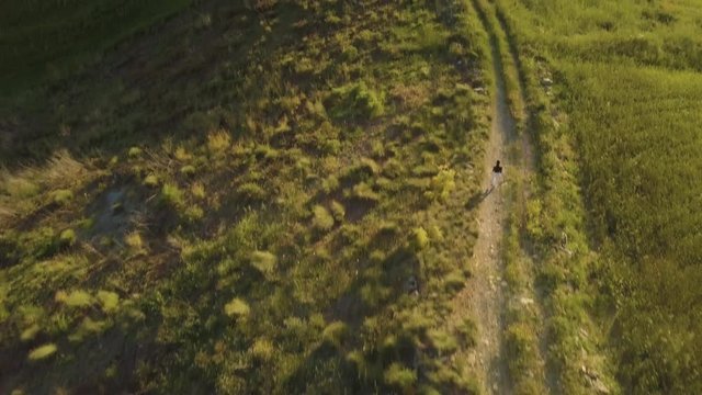Ragazza balla su una strada sterrata in cima alla collina in campagna al tramonto.