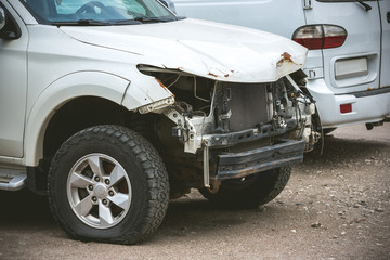 Broken and crashed modern white car after an accident on street, damaged automobile after collision...