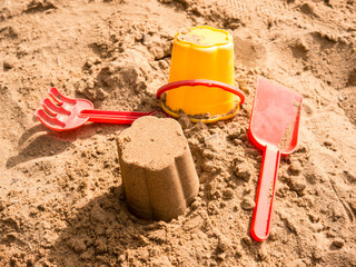 Bucket, puddle and rake in kid's sandbox top view