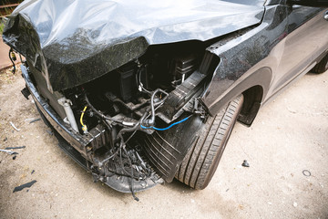 Broken and crashed modern black car after an accident on street, damaged automobile after collision...