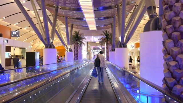 Passenger walking on the moving walkway in a modern, middle eastern airport