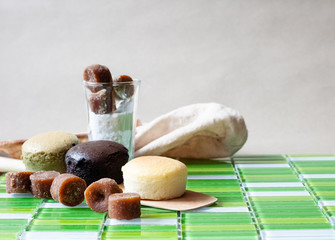 Cheese cakes, cup of icing and sugar cane with spatula and filter bag on tile floor. Sweetmeat and bakery concept. Original, choco and macha flavor.