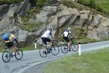 Fototapeta premium Cyclists ride on a mountain road in the Alps.