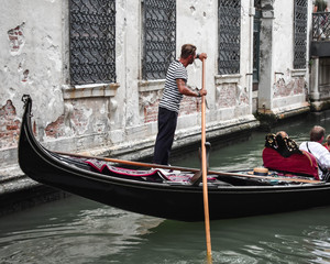 Fototapeta na wymiar Gondolier and his gondola, a typical scene in Venice.