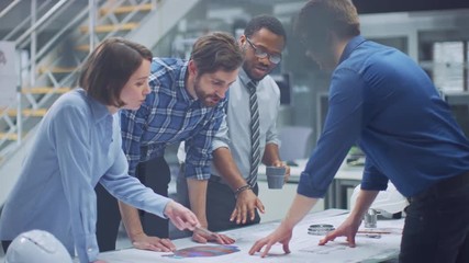 In the Industrial Engineering Facility: Diverse Group of Engineers, Technicians, and Specialists on a Meeting, Have Discussion, Analyze Engine Design Technical Drafts that are Lying on the Table - Powered by Adobe