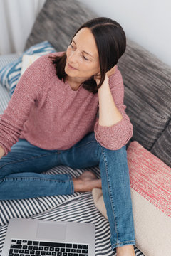 Thoughtful woman relaxing barefoot on a sofa