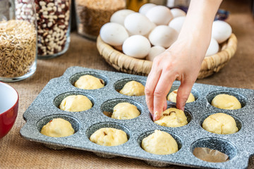 Cook's hand puts dough in cupcake baking dish