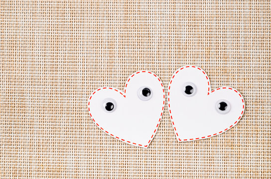 White heart paper with eyes on wooden mat background.
