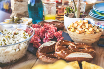 Close up view of many foods on a wooden table. Viande multicolor ready for a party. Apetizing colorful buffet. Summer aperitif, joy and family holidays, dinner on the terrace. Light lunch to share.
