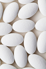 Pile of white drug pills laying on white background