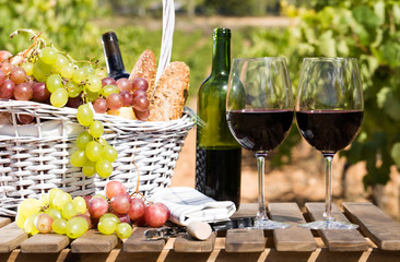 still life with glass of red wine grapes and picnic basket on table