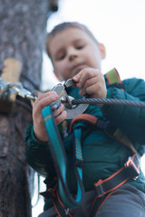 Obraz premium Little boy in a rope park. Active physical recreation of the child in the fresh air in the park. Training for children.