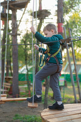 Obraz premium Little boy in a rope park. Active physical recreation of the child in the fresh air in the park. Training for children.