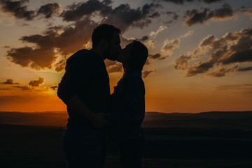 Silhouette of man and woman kissing at sunset