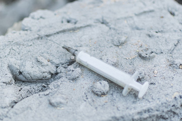 Addict syringe on concrete background.