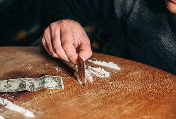 Man devides cocaine with a dollar note. Drugs addict dealer.  Dangerous habit. Unhealthy life...
