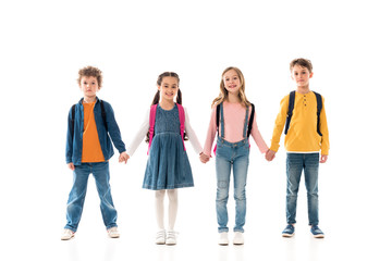 Obraz premium full length view of schoolchildren with backpacks holding hands isolated on white