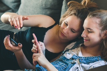 Young women using mobile phones watching music clip, texting, messaging