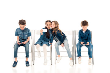 kids in denim clothes sitting on chairs and taking selfie on white